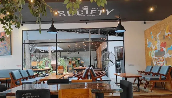 Suasana interior industrial modern Society Coffee House Purwokerto dengan meja kerja luas dan pencahayaan estetik